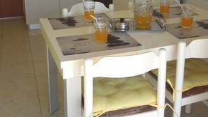 A small kitchen with a dining table set for four, a refrigerator, and a coffee maker. - Apartments Elide (Rabac)