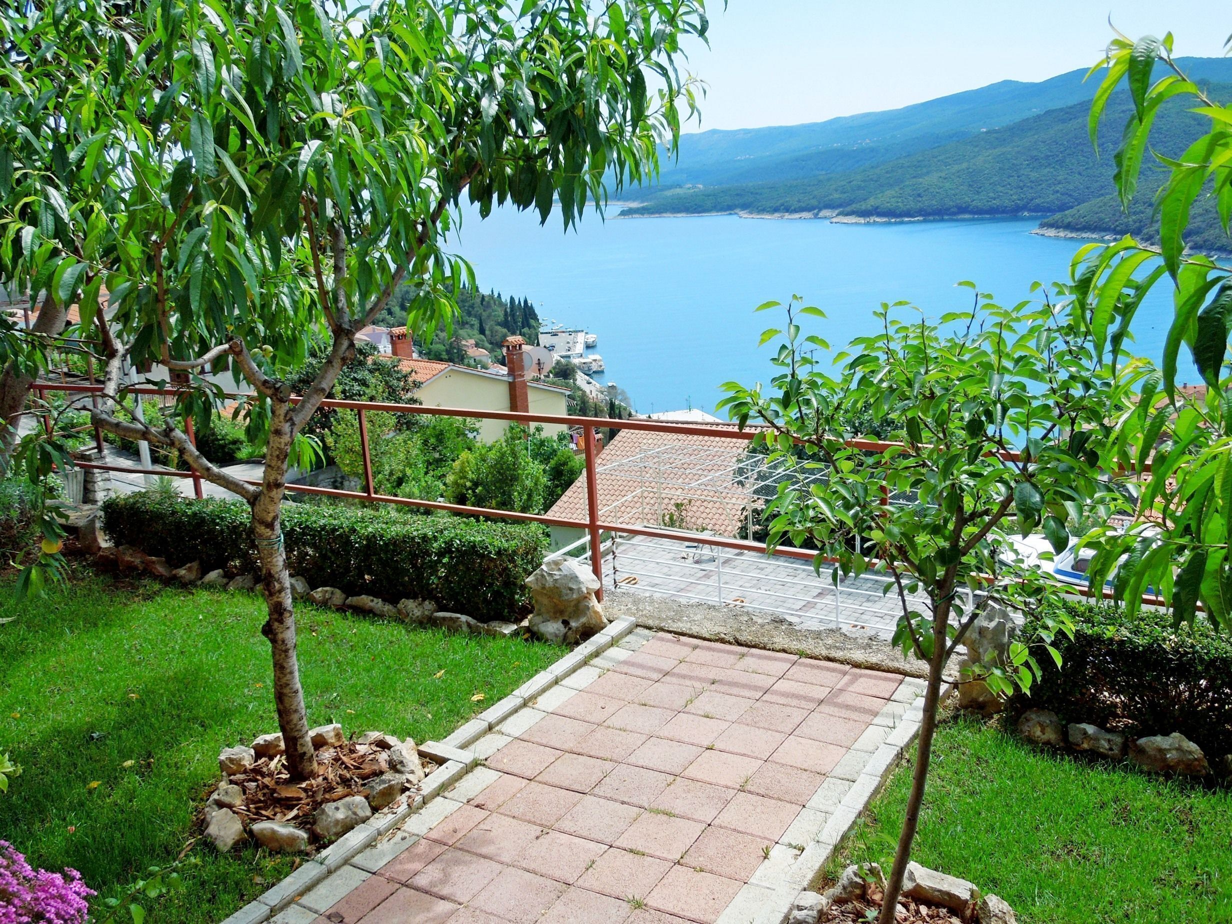 A paved pathway leading to a scenic overlook with a view of a lake and distant mountains.