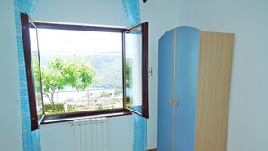A room with a large window, wooden flooring, a wardrobe, and a bed. - Apartments Elide (Rabac)