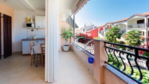 Un balcón con vistas a edificios cercanos y una pequeña cocina con microondas y una mesa.
