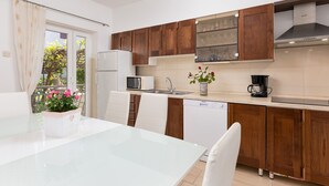 A modern kitchen with wooden cabinets, a white refrigerator, a microwave, and a coffee maker. - Apartment Loredana (Porec)