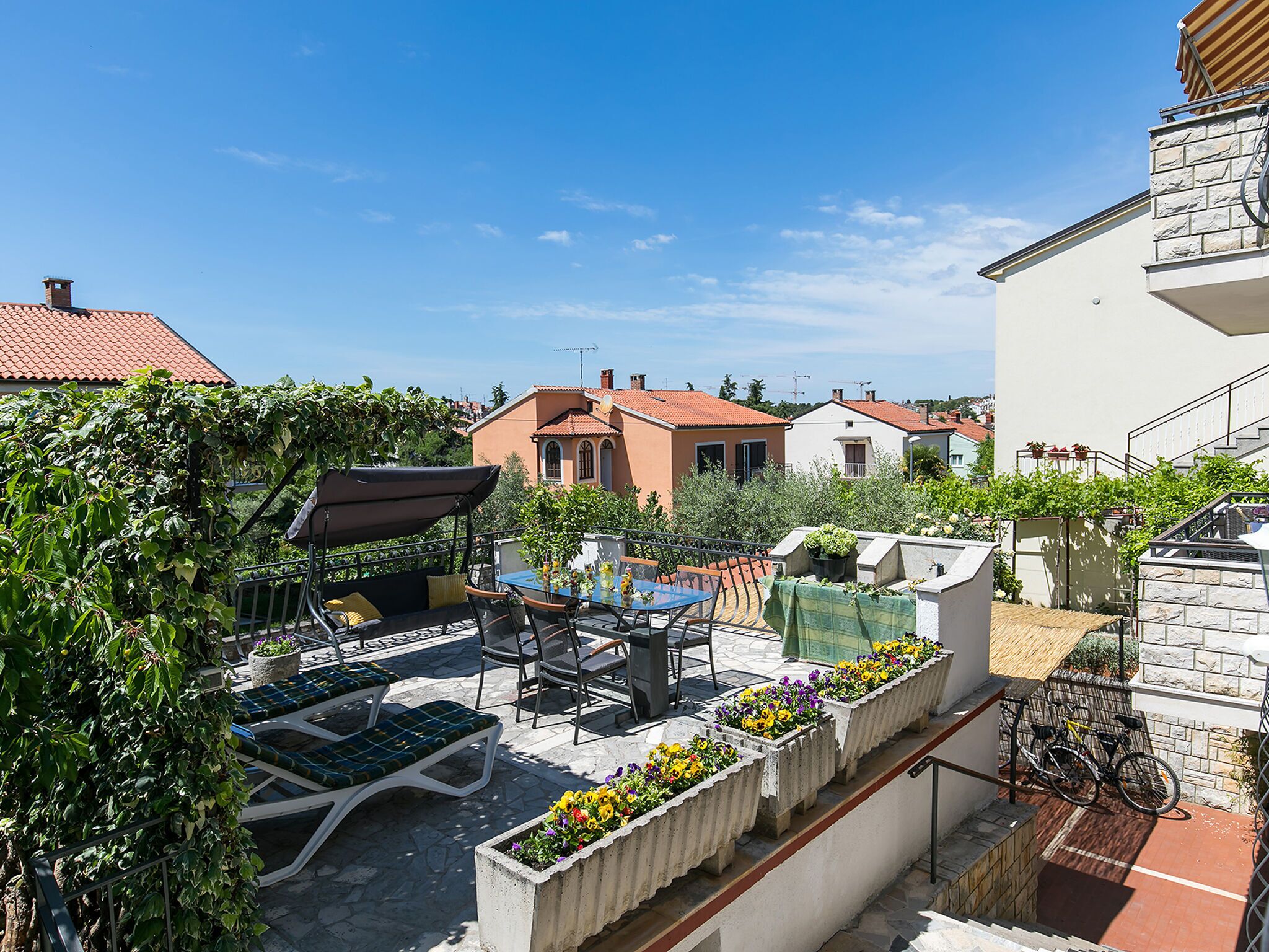 Une terrasse sur le toit, aménagée avec des chaises longues, une table et des plantes en pot.