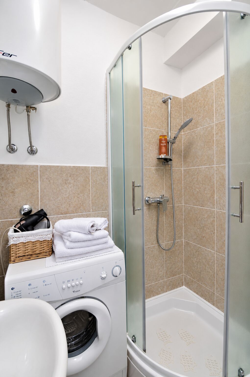 Un baño moderno con ducha de vidrio, lavadora y un perchero para toallas.