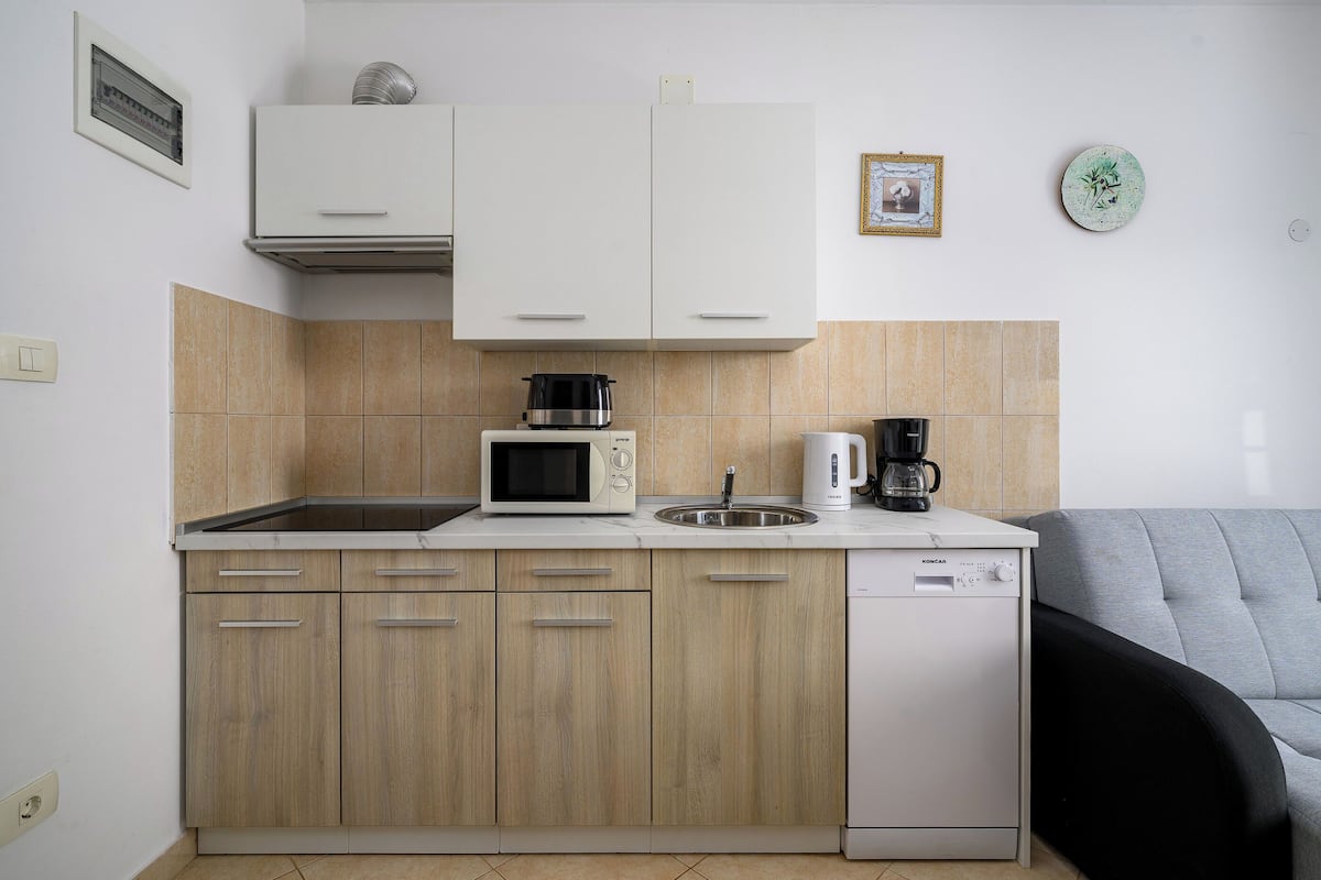 A compact kitchen with a microwave, coffee maker, and dishwasher.