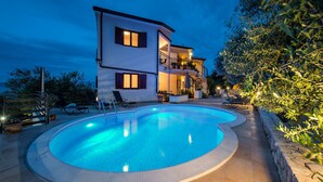 A two-story house with a swimming pool, outdoor furniture, and a well-lit balcony. - Apartments Wellness (Ravni)