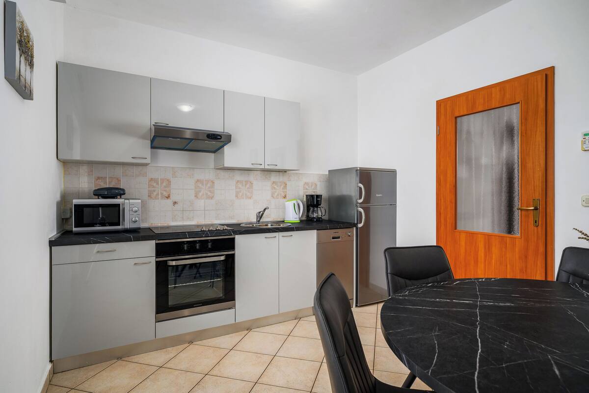 A compact kitchen with white cabinets, a microwave, a coffee maker, and a refrigerator.