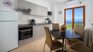 A modern kitchen with a dining area, a clock, and a view of the sea. - Apartments Wellness (Ravni)