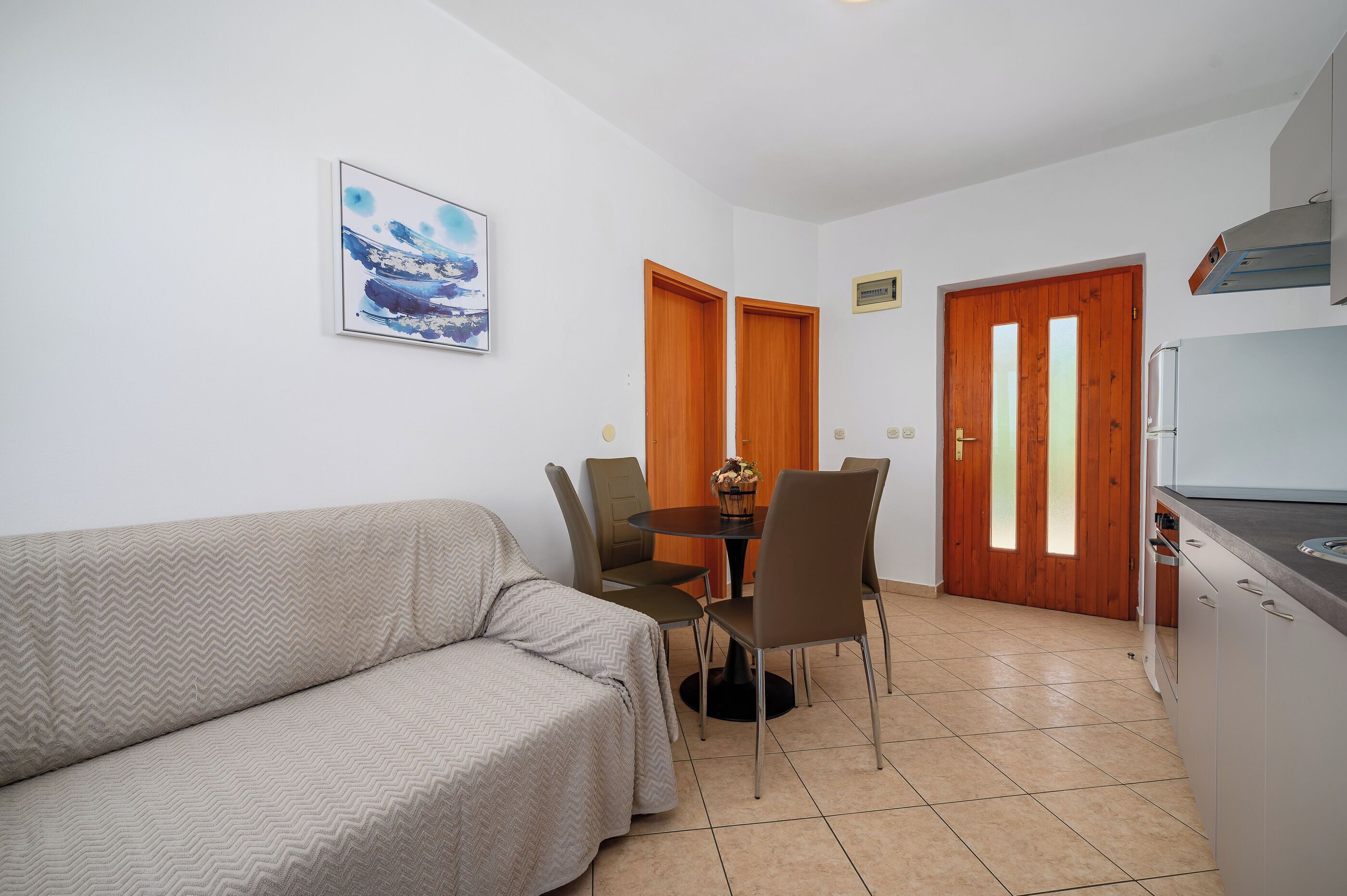 A compact living space with a sofa, dining table, chairs, and a kitchenette.