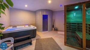 A spa room with a hot tub, a glass door leading to a sauna, and a wooden staircase. - Apartments Wellness (Ravni)