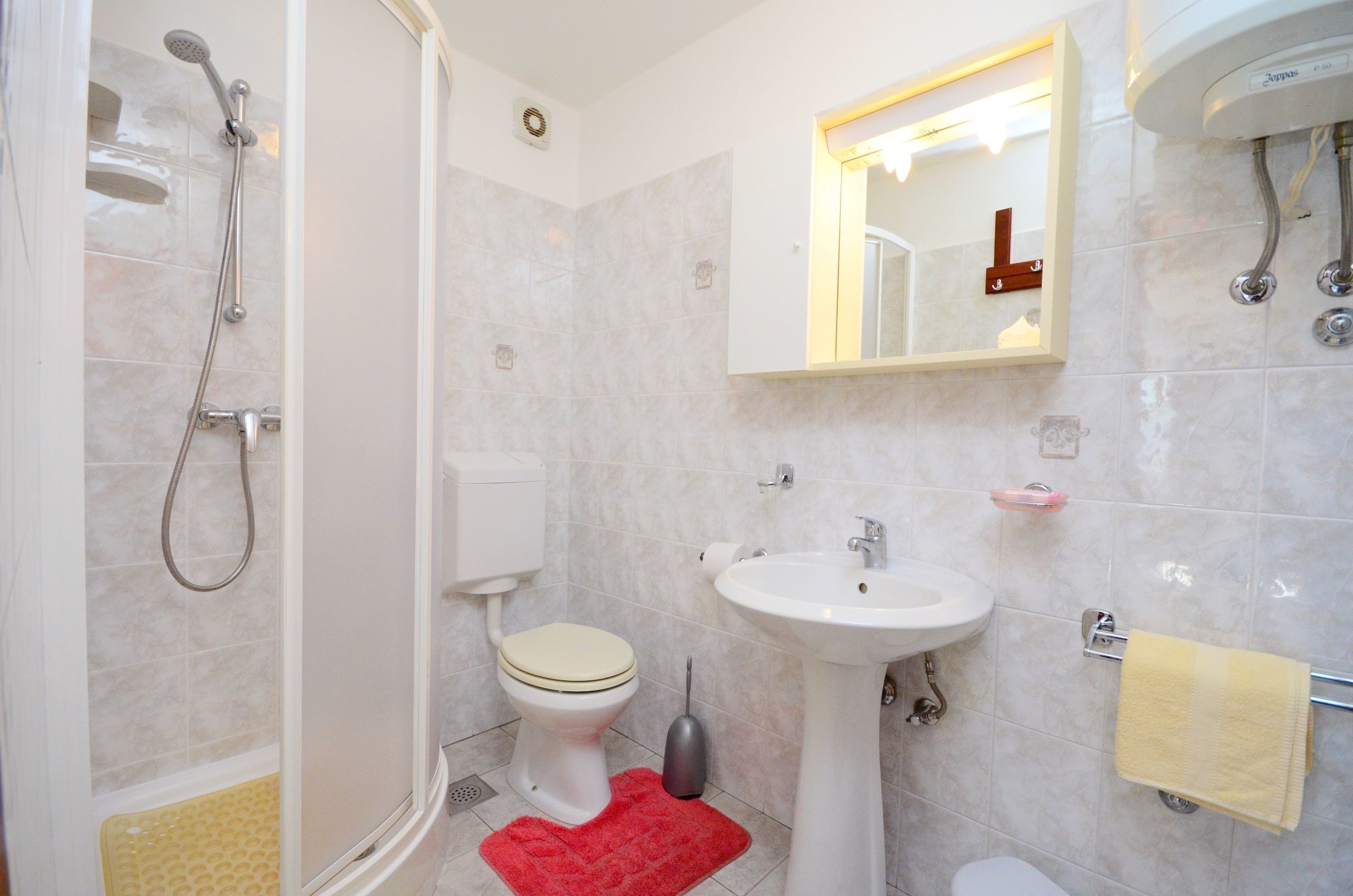 A bathroom with a shower, toilet, sink, and mirror.