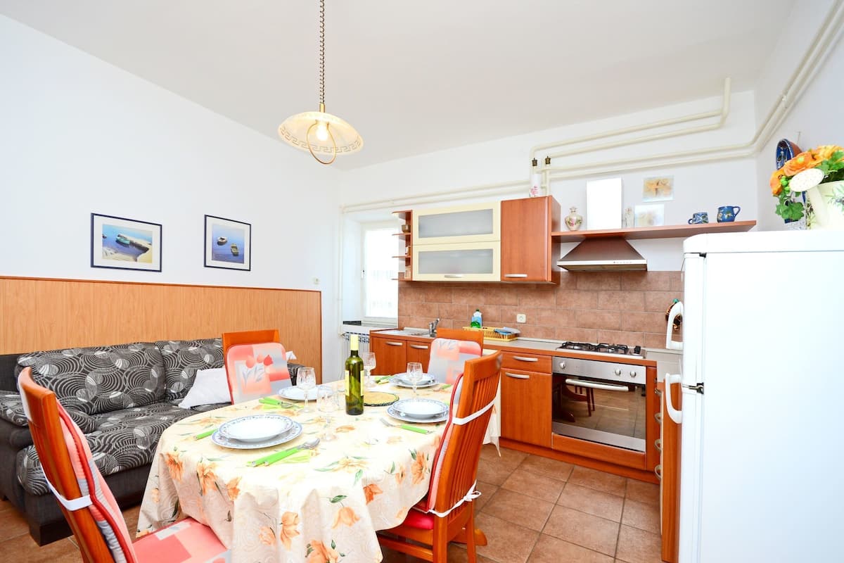A compact kitchen with a gas stove, oven, and a dining area with a table set for two.