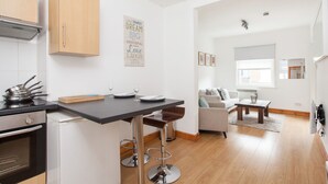 A modern kitchen with a dining area, a sofa, and a coffee table. - Basic Apartment for Two Amazing Location (London)