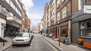 A street with parked cars, buildings, and a sign for a coffee shop. - Basic Apartment for Two Amazing Location (London)