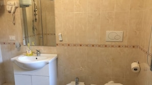 A bathroom with a sink, bidet, toilet, and a hairdryer mounted on the wall. - Near Termini Station (Rome)