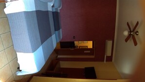 A staircase leading to a room with a bed, a ceiling fan, and a television. - Near Termini Station (Rome)