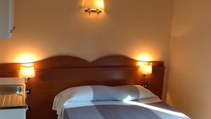 A hotel room with a bed, two bedside lamps, a ceiling fan, and a small table. - Near Termini Station (Rome)