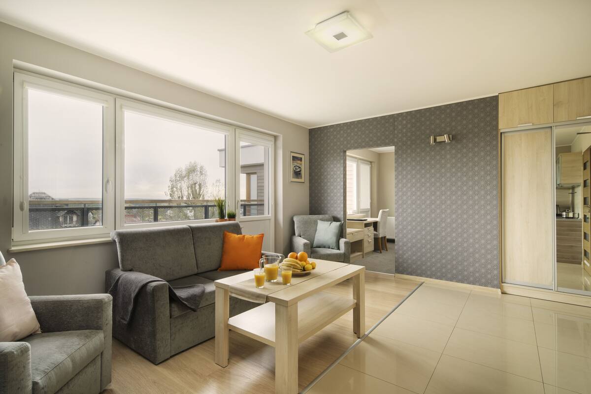 A modern living room with a sofa, coffee table, and a dining area.