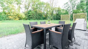 An outdoor patio with a rectangular table and six wicker chairs. - Beautiful apartment "chicken coop" in the countryside (Harrierwurp)