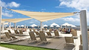 A beachside outdoor seating area with sun loungers and umbrellas, overlooking the ocean. - Pet Friendly 3BR Tarpon Pond Cottage! Close to Beach/Pools (Seabrook Island)