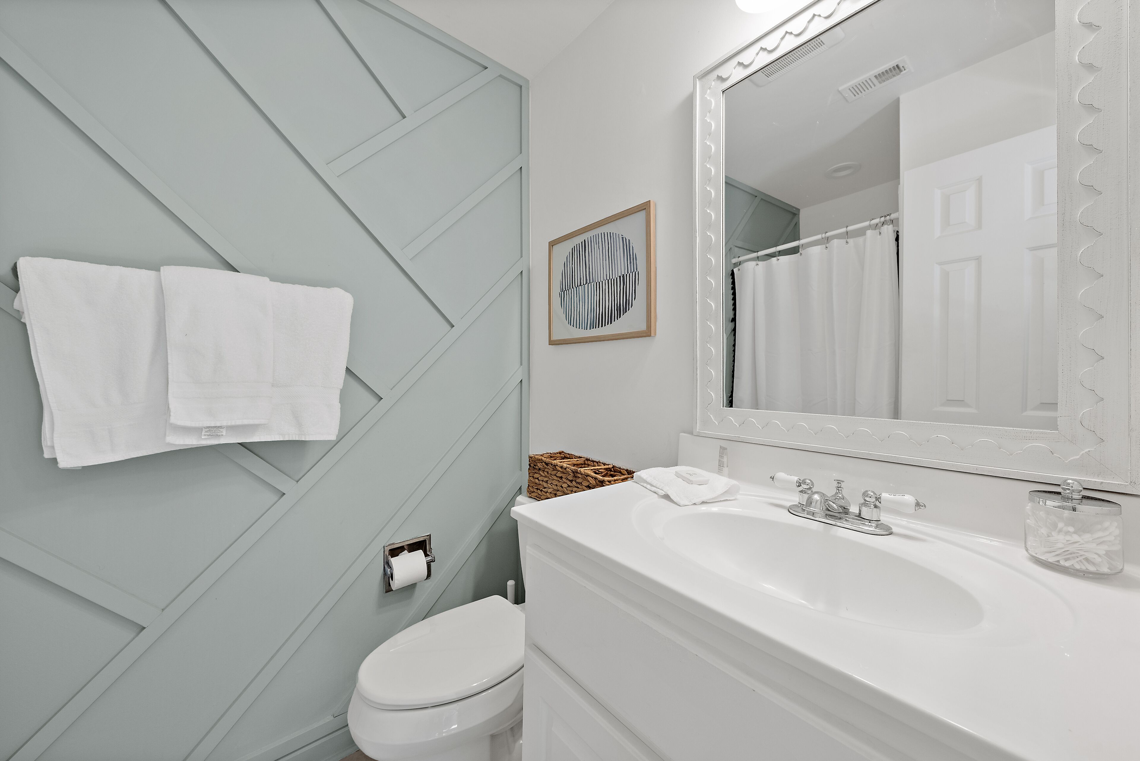 Une salle de bain avec un lavabo blanc, un miroir, des toilettes et un porte-serviettes.