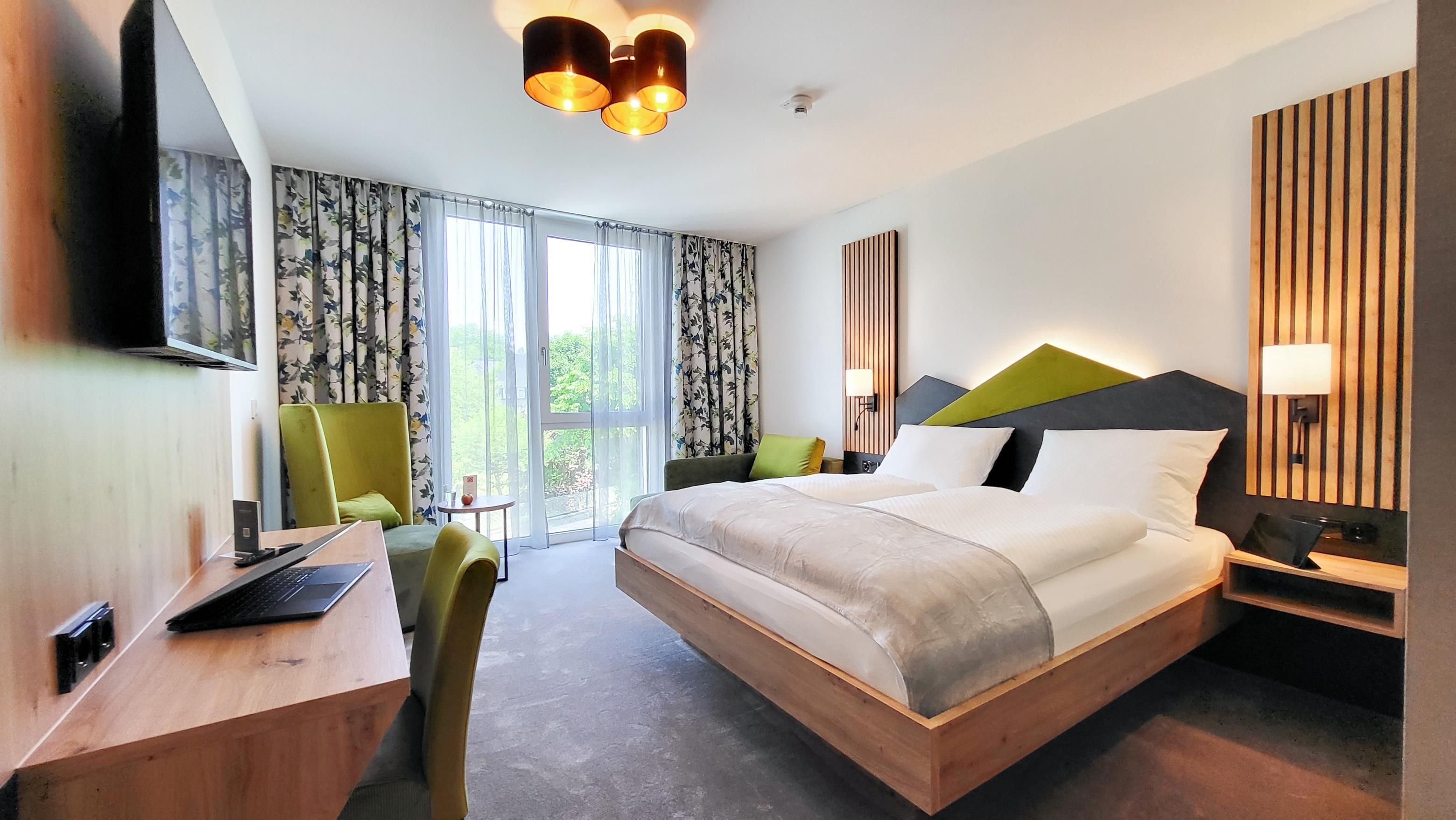 Une chambre d’hôtel moderne équipée d’un grand lit, d’un bureau, d’une chaise et d’un téléviseur.