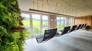 Une pièce avec une rangée de chaises disposées face à une grande fenêtre donnant sur un paysage verdoyant.