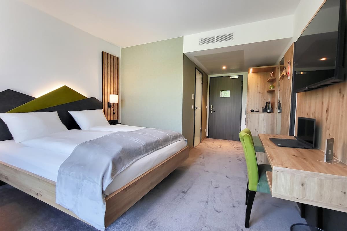 Een moderne hotelkamer met een groot bed, een bureau met stoel, een televisie en een houten accentmuur.
