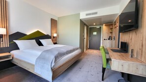 A modern hotel room with a large bed, a desk with a chair, a TV, and a wooden accent wall. - Mountain View Hotel Willingen, BW Signature Collection (Willingen)