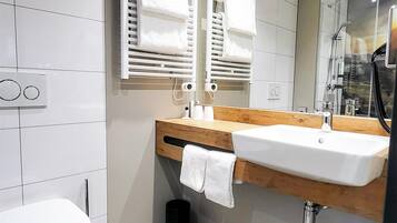 Ein modernes Badezimmer mit einer weißen Toilette, einem Holzwaschtisch mit einem Becken und einem Spiegel darüber.