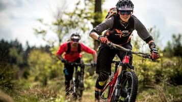 Two mountain bikers on a trail with trees in the background.