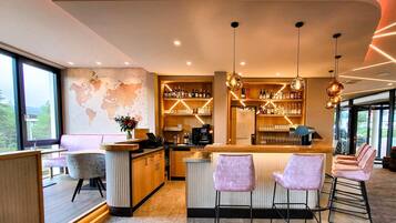 A modern bar area with a world map on the wall, bar stools, and a variety of bottles.