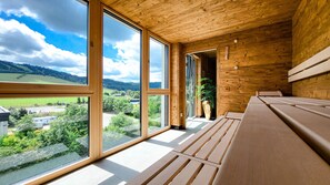 Ein Zimmer mit großen Fenstern, einer Holzbalkendecke und einer Sitzbank.