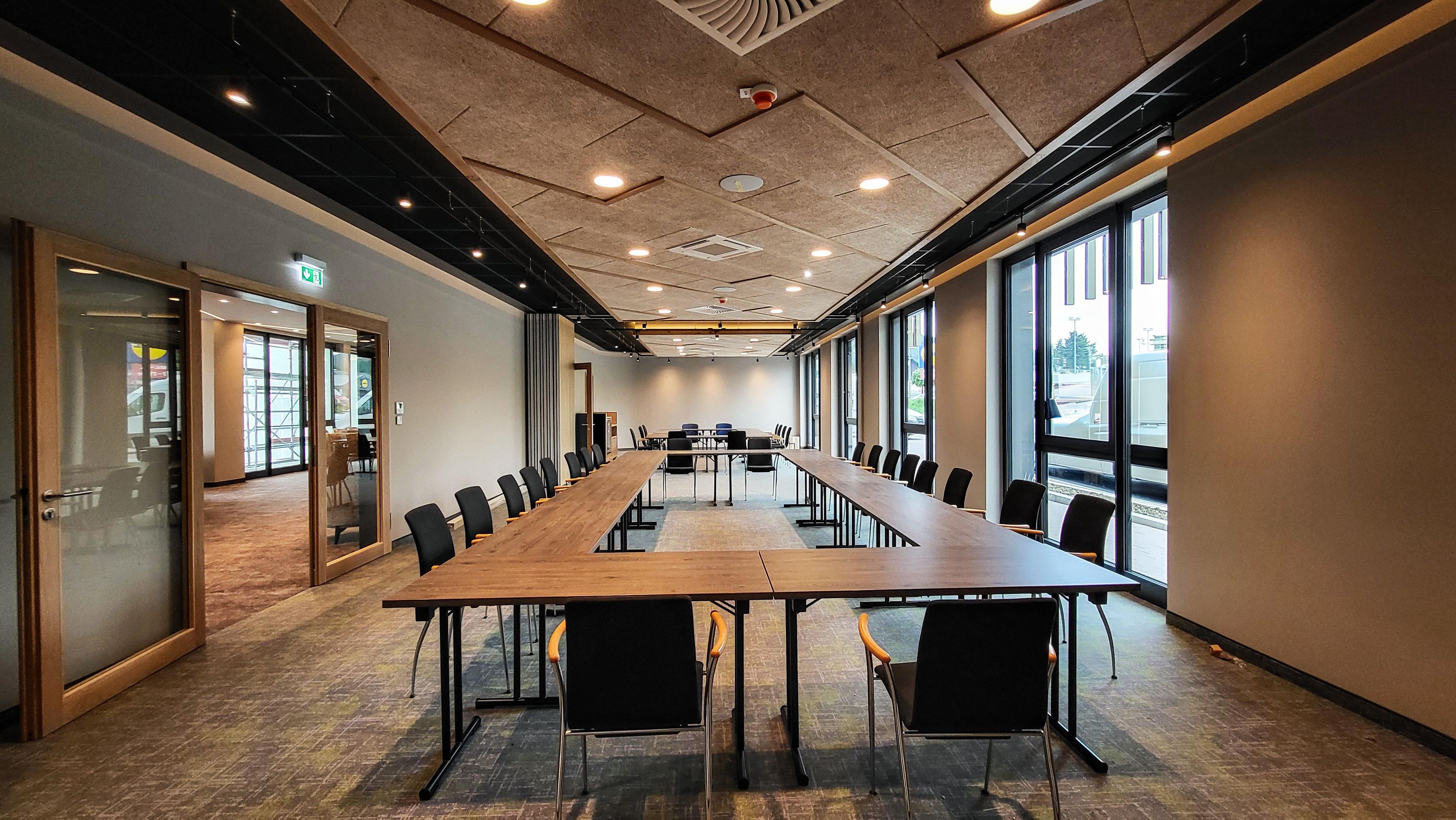 A conference room with a long table, chairs, and large windows.