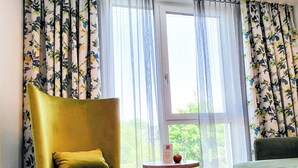 Una habitación con un sillón amarillo, un sofá verde y una mesita con una manzana roja.