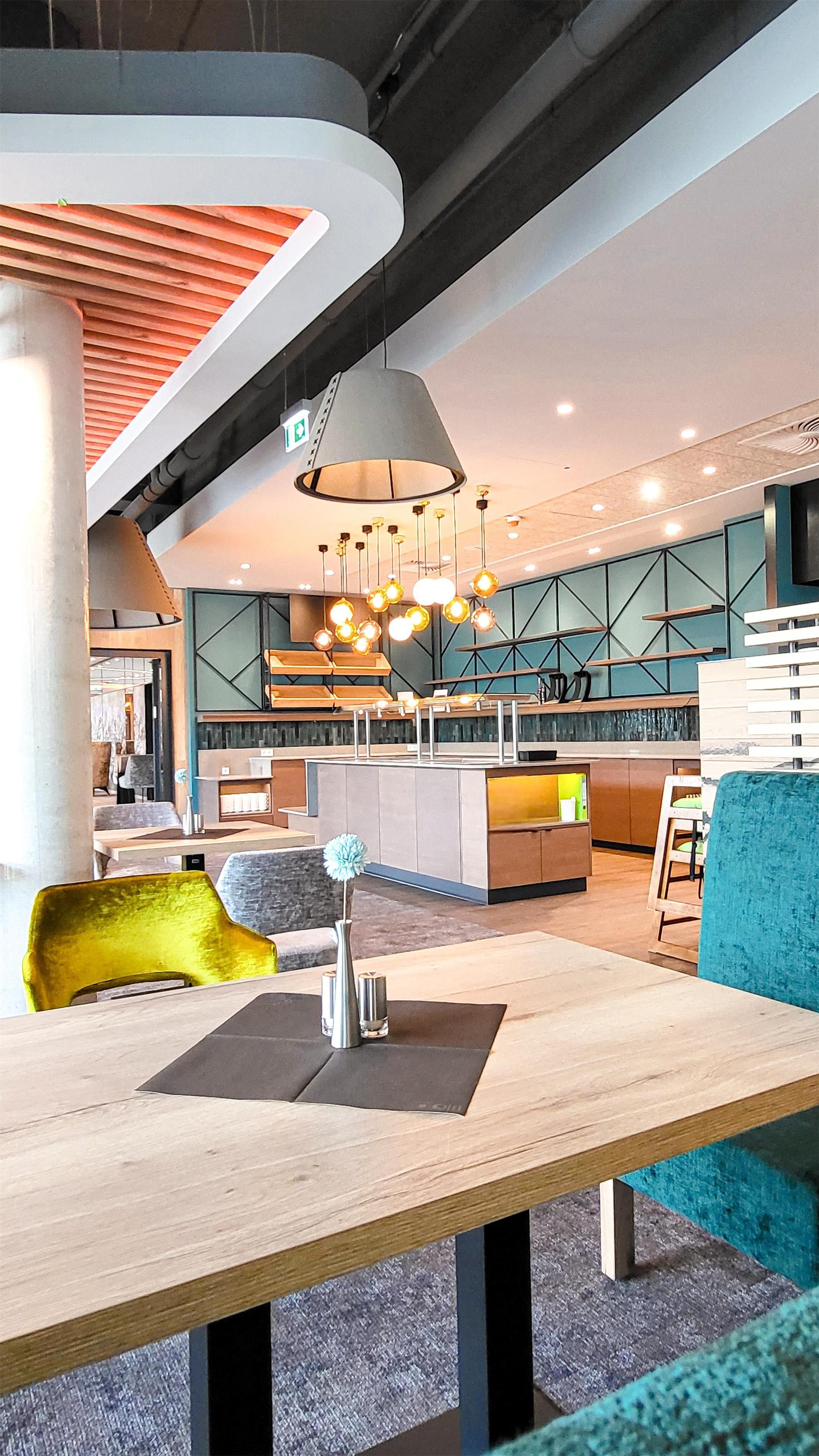 Een modern interieur met een gebogen plafond, een centraal gelegen eethoek met een houten tafel, en een bar met krukken.
