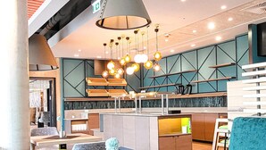 Un interior moderno con techo curvo, una zona de comedor central con mesa de madera y una barra con taburetes.