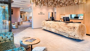 Un área de recepción moderna con un mostrador de madera, asientos y un ventanal grande.