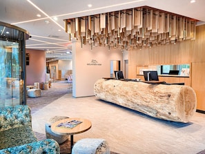 Un espace d’accueil moderne avec un comptoir de réception en bois, des sièges et une grande fenêtre.