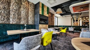 Un interior de restaurante moderno con diferentes opciones de asientos, incluyendo boxes y mesas, y una pared decorativa con textura natural.
