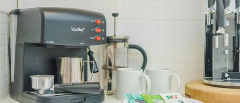 A coffee maker with a control panel, a coffee pot, a white mug, and a plate with coffee pods.