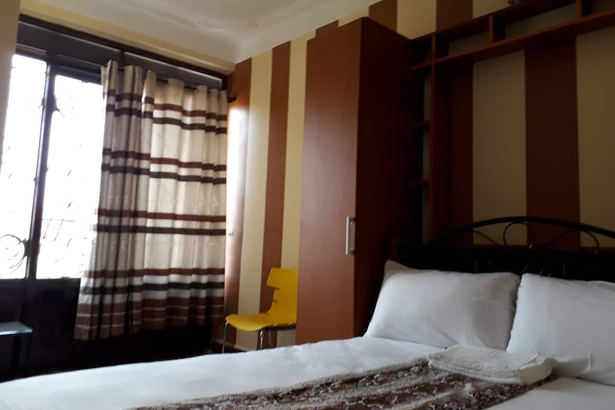 A hotel room with a bed, a chair, and a window with curtains.