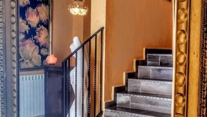 A staircase with a black railing leading to a landing with a chandelier.