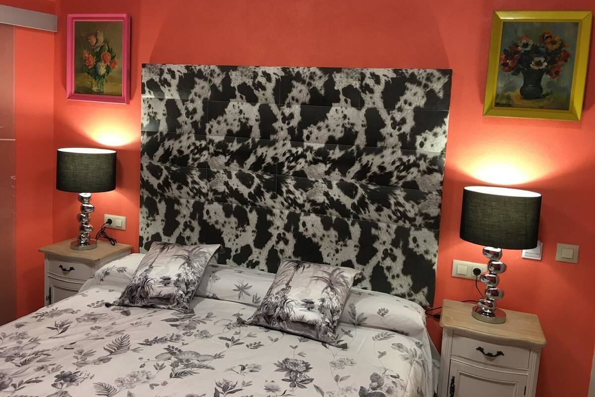 A bedroom with a bed, two bedside tables, and a headboard with a cowhide pattern.