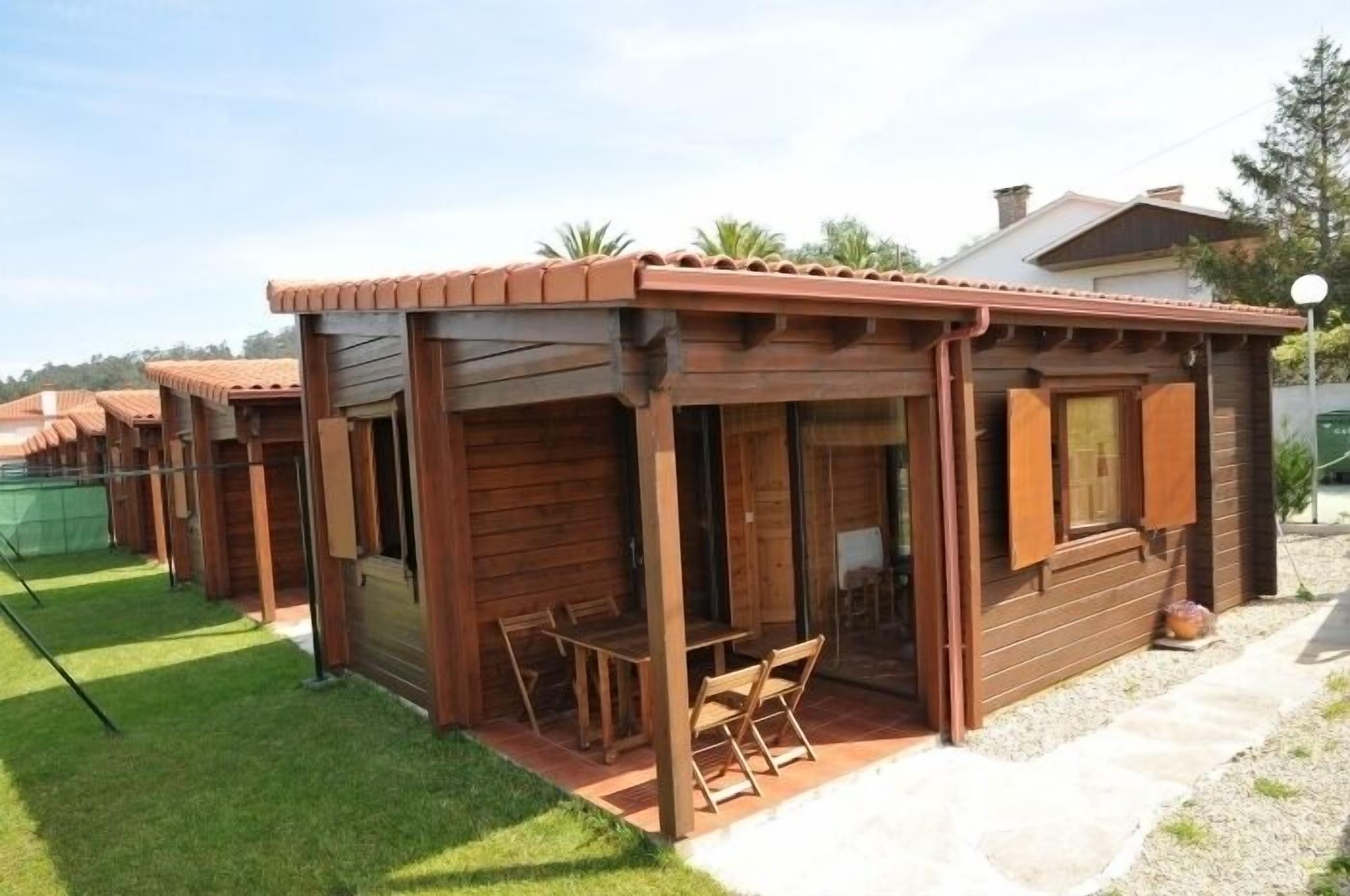 Una cabaña de madera con un patio amoblado, que incluye una mesa y sillas.
