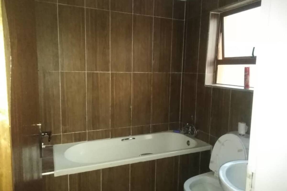 A bathroom with a bathtub, toilet, and a window.