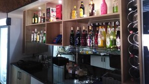 Zona de bar con estantes llenos de botellas de licores y una bodega de vinos.