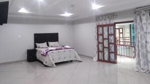 Un dormitorio con cama, mesita de noche, armario y puerta corrediza de vidrio que da a un espacio exterior.