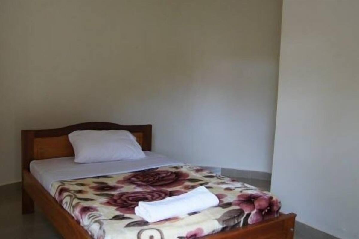 A single bed with a wooden headboard in a room with plain walls.
