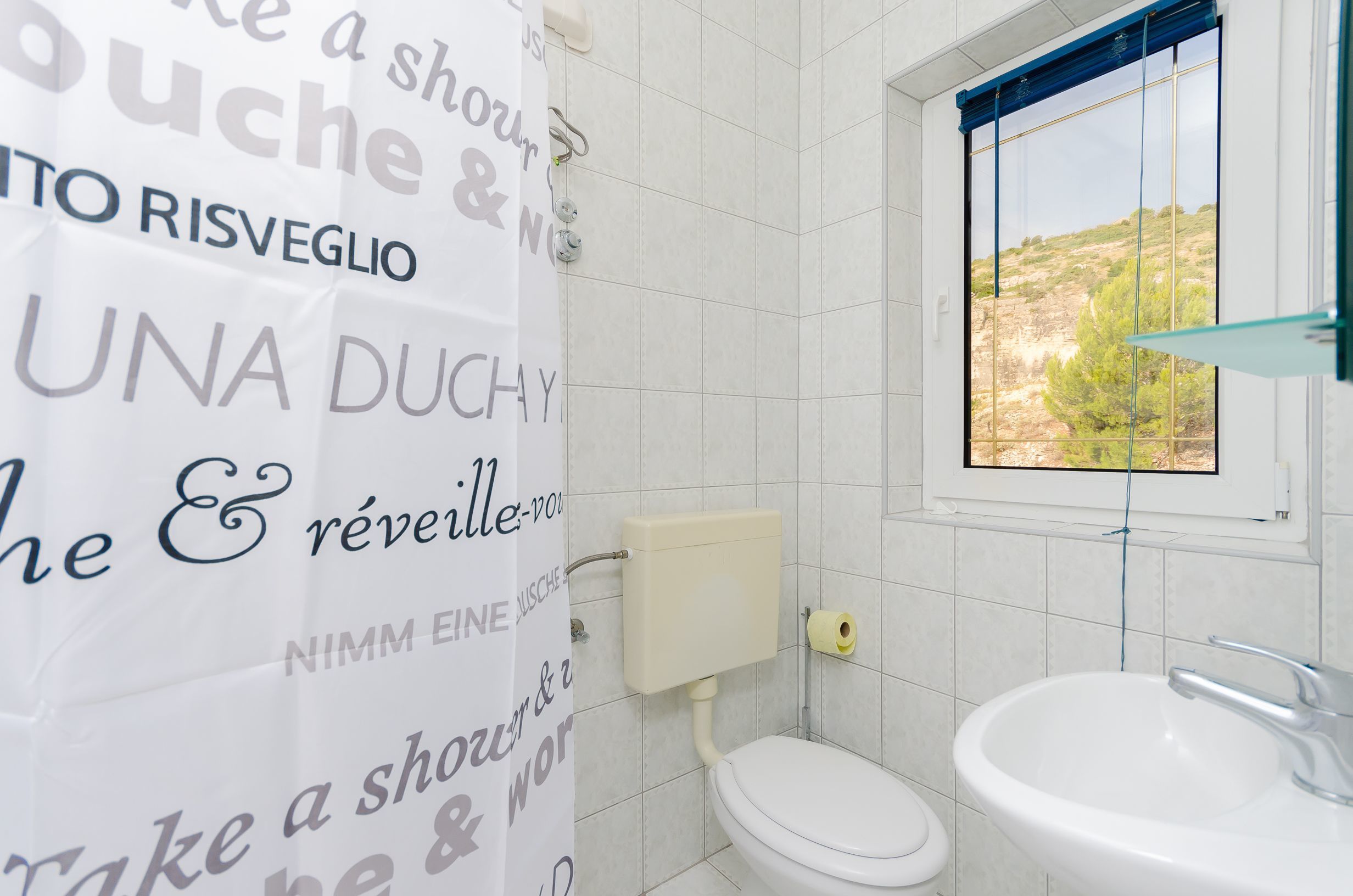 Un bagno con il water, un lavandino e una finestra vista paesaggio.