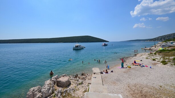 Una spiaggia con acque cristalline, imbarcazioni e persone.